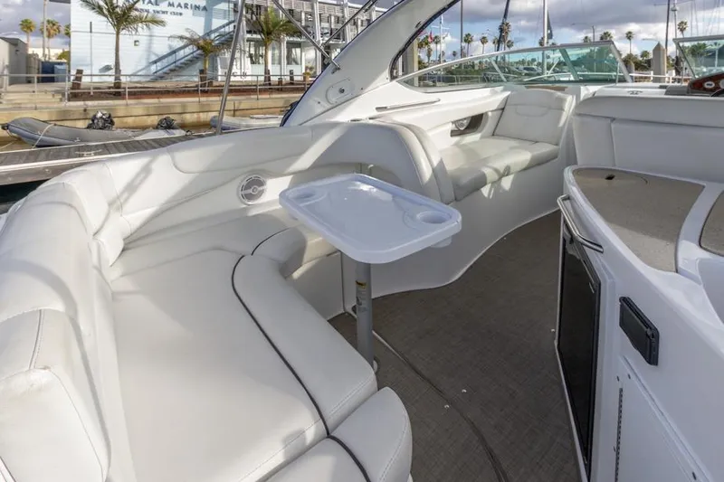 Slide: The Image of 2013 Rinker 290 Express Cruiser interior with white seating and small table. - 9