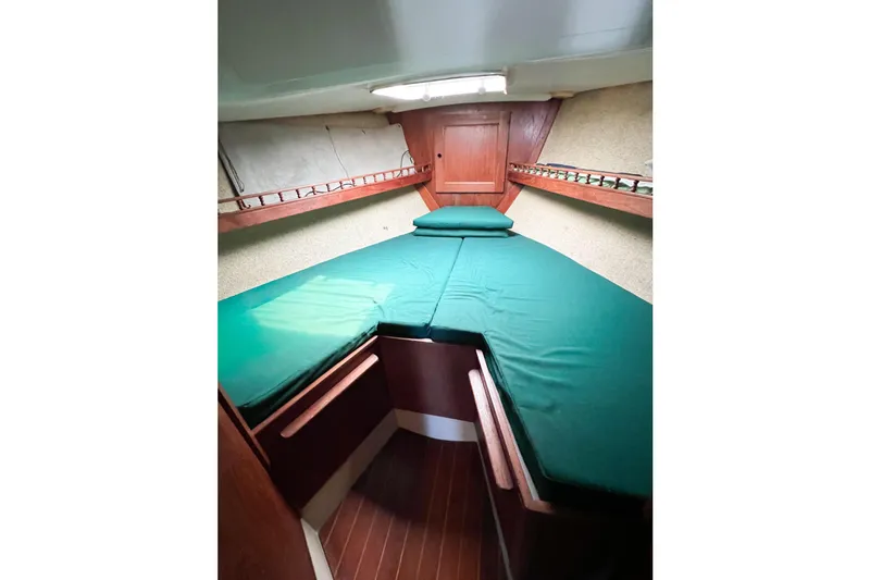 Slide: The Image of 1978 CAL 34 sailboat cabin with green bedding and wooden interior. - 16