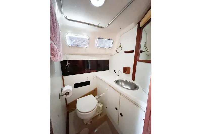 Slide: The Image of 1978 CAL 34 sailboat bathroom with sink, toilet, and portholes. - 17