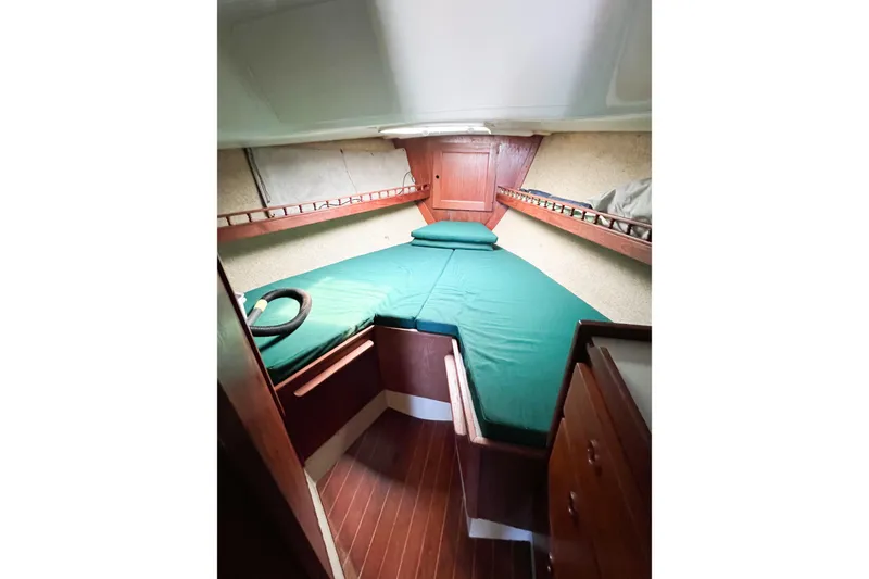 Slide: The Image of 1978 CAL 34 sailboat cabin with green bedding and wooden interior. - 18