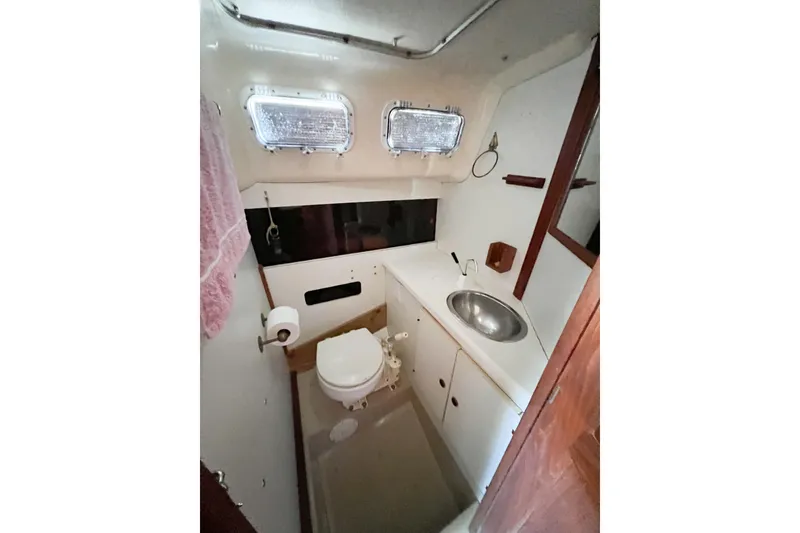 Slide: The Image of 1978 CAL 34 sailboat bathroom with sink, toilet, and portholes. - 19