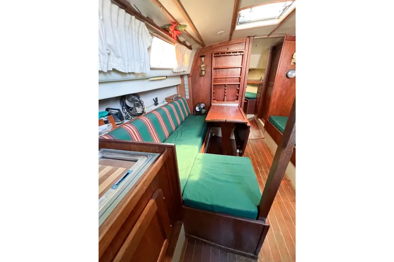 Slide: The Image of 1978 CAL 34 sailboat interior with green cushions, wooden cabinetry, and striped upholstery. - 29