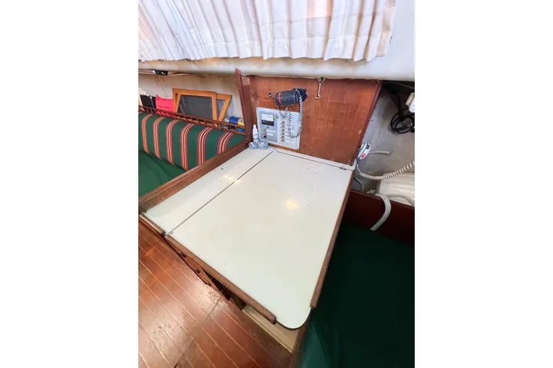 Slide: The Image of Interior of a 1978 CAL 34 sailboat with a wooden table and striped seating. - 31