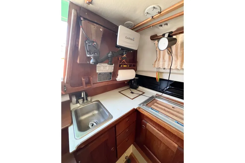 Slide: The Image of 1978 CAL 34 sailboat kitchen with sink, wooden cabinets, and Garmin equipment. - 33