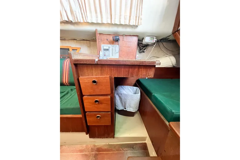 Slide: The Image of 1978 CAL 34 sailboat interior with wooden desk, drawers, and green cushions. - 37
