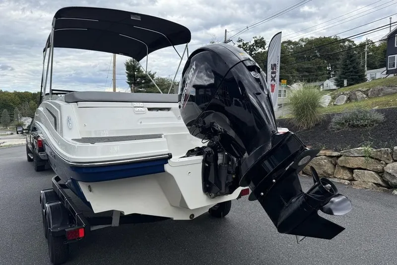 Slide: The Image of 2026 Bayliner VR6 Bowrider OB with outboard motor on a trailer, parked outdoors. - 13