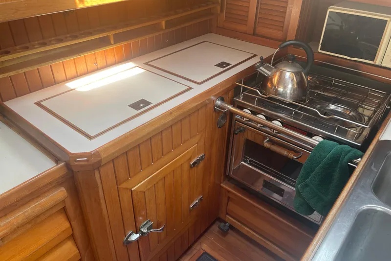 Slide: The Image of 1984 Slocum 43 yacht galley with wooden cabinetry, stove, and kettle. - 16