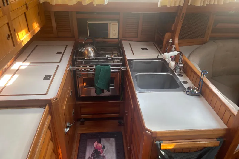 Slide: The Image of 1984 Slocum 43 yacht kitchen with stove, double sink, and wooden cabinetry. - 17