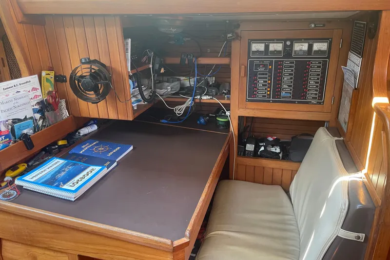 Slide: The Image of Navigation station inside 1984 Slocum 43 sailboat with control panels and marine guides. - 24