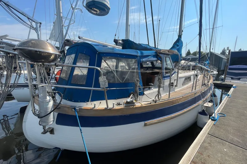 Slide: The Image of 1984 Slocum 43 sailboat docked, featuring blue and white design with wooden deck accents. - 6