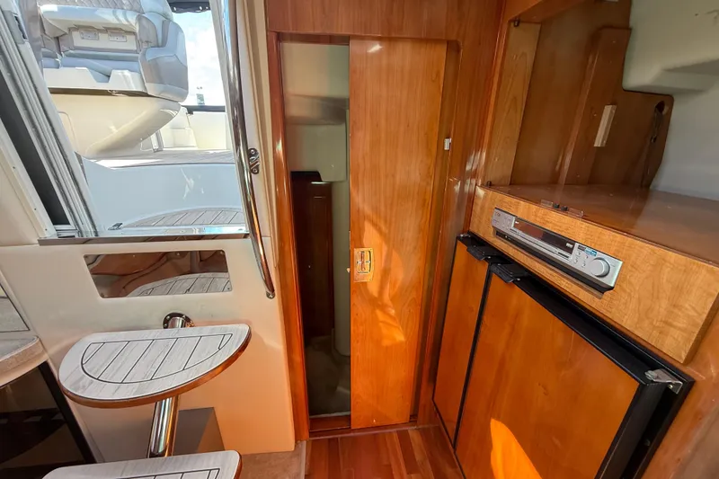 Slide: The Image of 2004 Regal Commodore 3860 yacht interior with wood finish, compact kitchen, and seating area. - 19