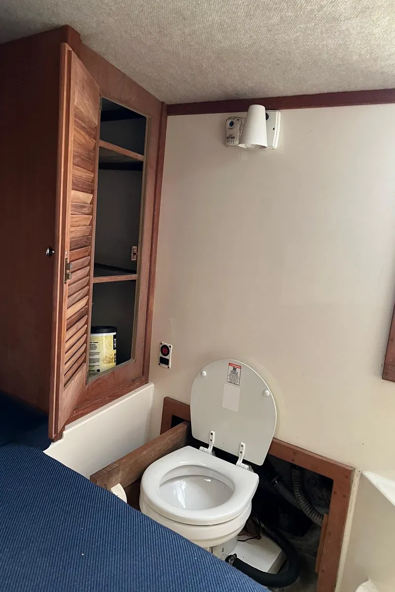 Slide: The Image of 2002 Carolina Classic 25 Classic boat interior with toilet and wooden storage cabinet. - 7