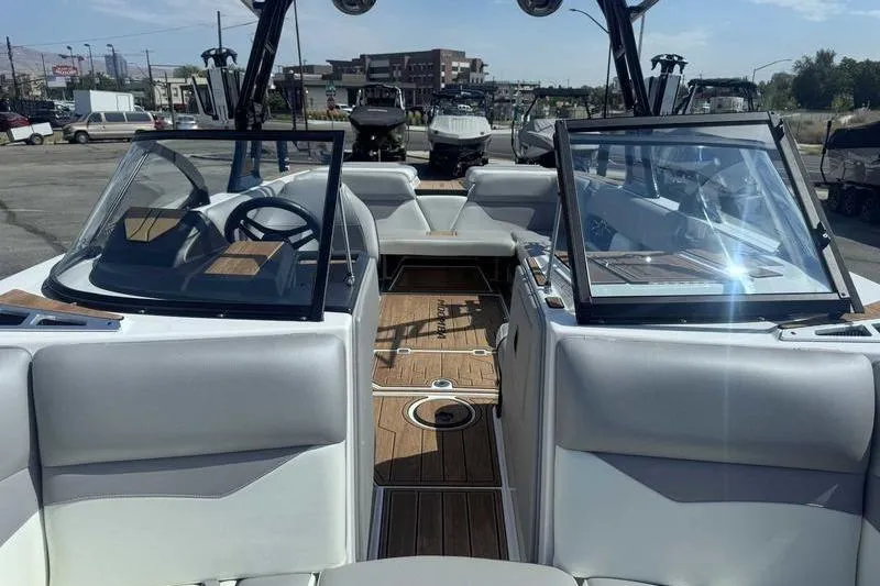 Slide: The Image of 2022 Moomba Mojo boat interior with open windshield, showcasing seating and steering wheel. - 12