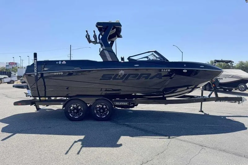 Slide: The Image of 2026 Supra SL boat on trailer, sleek black design, parked outdoors. - 5
