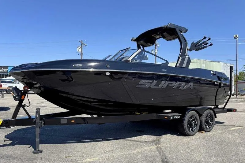 Slide: The Image of 2026 Supra SL boat on trailer, sleek black design, parked outdoors. - 8