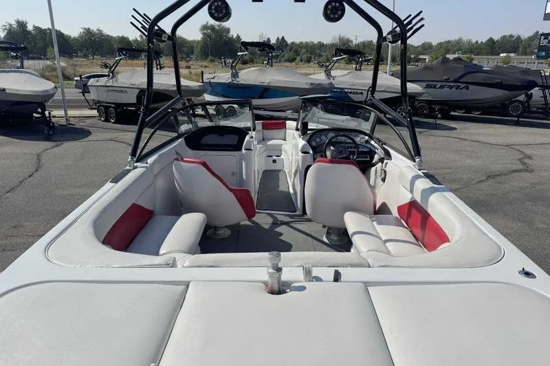 Slide: The Image of 2000 Tigé 2300V Limited boat interior with red and white seating, parked among other boats. - 8