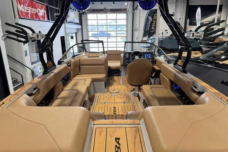 Slide: The Image of 2026 Moomba Mojo boat interior with tan seating and modern dashboard in showroom. - 12