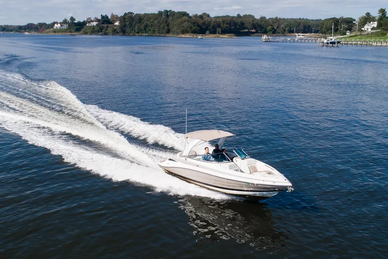 Slide: The Image of 2017 Crownline 285 SS speedboat cruising on a scenic lake with lush shoreline. - 15