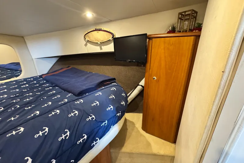Slide: The Image of 1996 Silverton 372 Motor Yacht cabin with nautical bedding and wooden cabinet. - 31