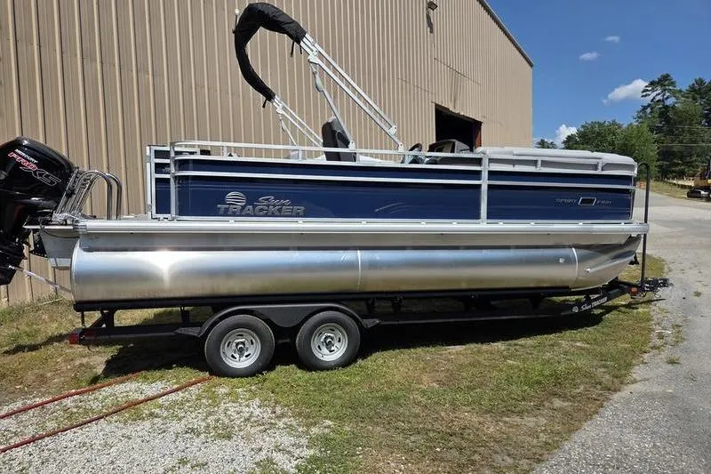 Slide: The Image of 2026 Sun Tracker SF 20 DLX pontoon boat on trailer, parked near a building. - 4