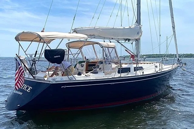 Slide: The Image of 1985 Sabre 36 sailboat on water, featuring a sleek design and American flag. - 1