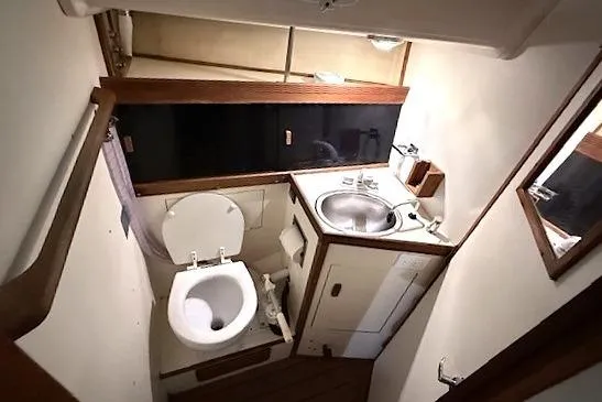 Slide: The Image of Compact bathroom in 1985 Sabre 36 yacht with toilet, sink, and wooden accents. - 20