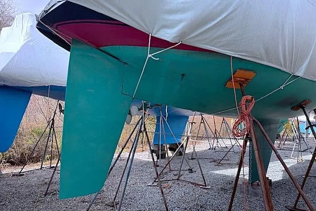 Slide: The Image of 1985 Sabre 36 sailboat on stands, covered, with visible keel and rudder. - 21