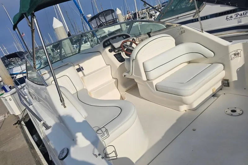 Slide: The Image of 1999 Sea Ray 270 Sundancer boat interior with white seating and steering wheel. - 2