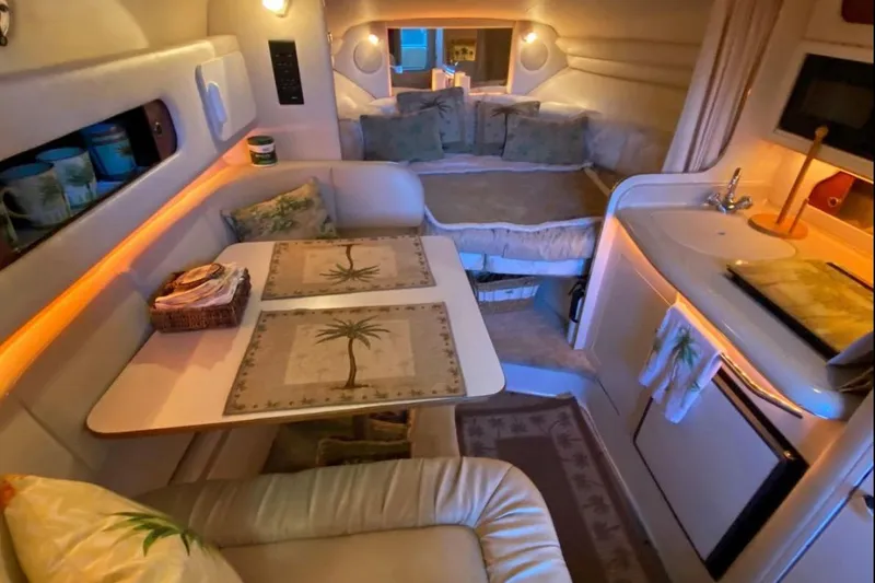 Slide: The Image of 1999 Sea Ray 270 Sundancer cabin interior with cozy seating, kitchenette, and ambient lighting. - 3