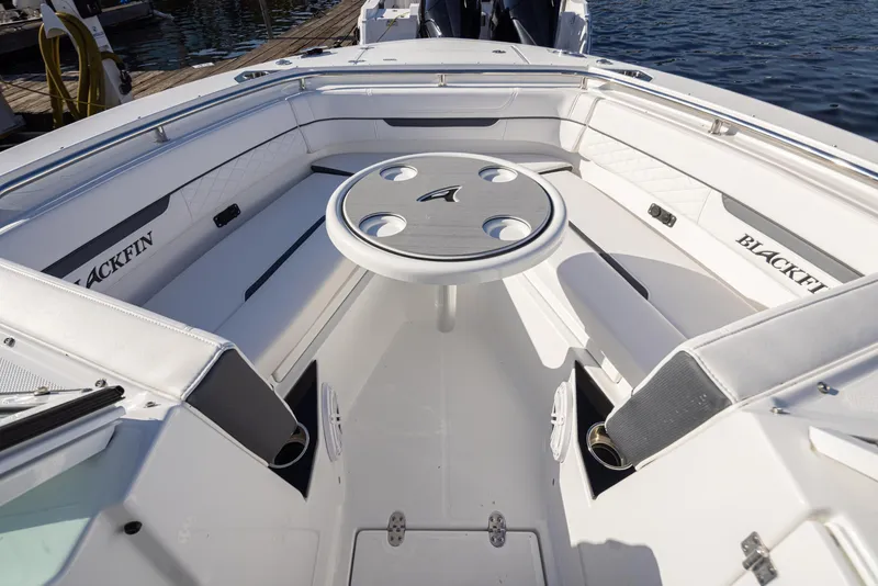 Slide: The Image of 2021 Blackfin 252DC boat interior with seating and table, docked by the water. - 20
