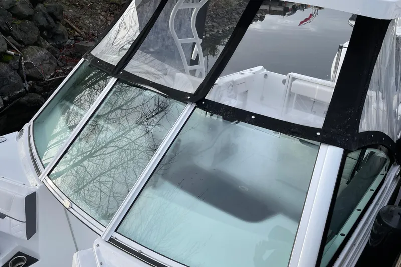 Slide: The Image of 2021 Blackfin 252DC boat with clear windshield, docked near rocky shoreline. - 29