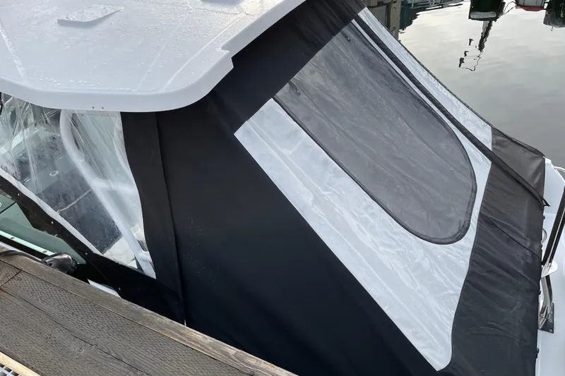 Slide: The Image of 2021 Blackfin 252DC boat with black and white canopy, docked by the water. - 31
