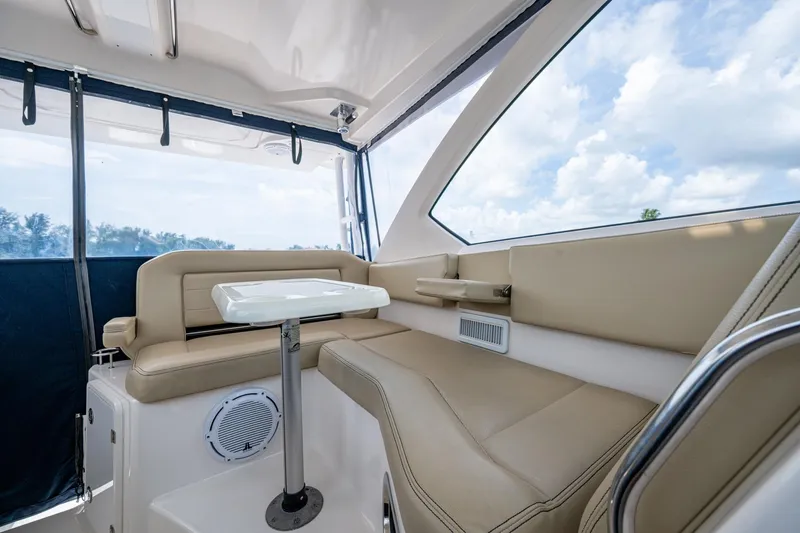 Slide: The Image of Luxurious Pursuit boat interior with beige seating, table, and panoramic windows. - 10