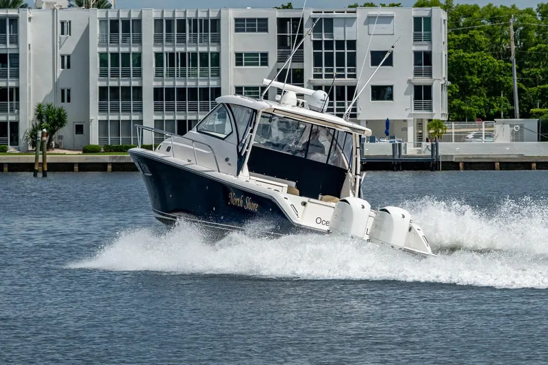 Slide: The Image of Pursuit boat cruising on water near modern waterfront buildings. - 11