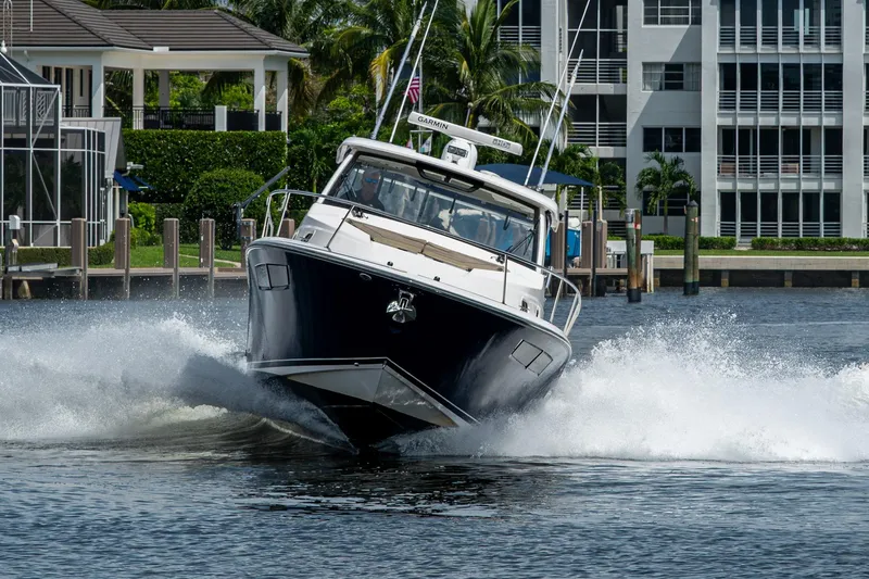 Slide: The Image of Pursuit boat speeding on water near waterfront homes and palm trees. - 12