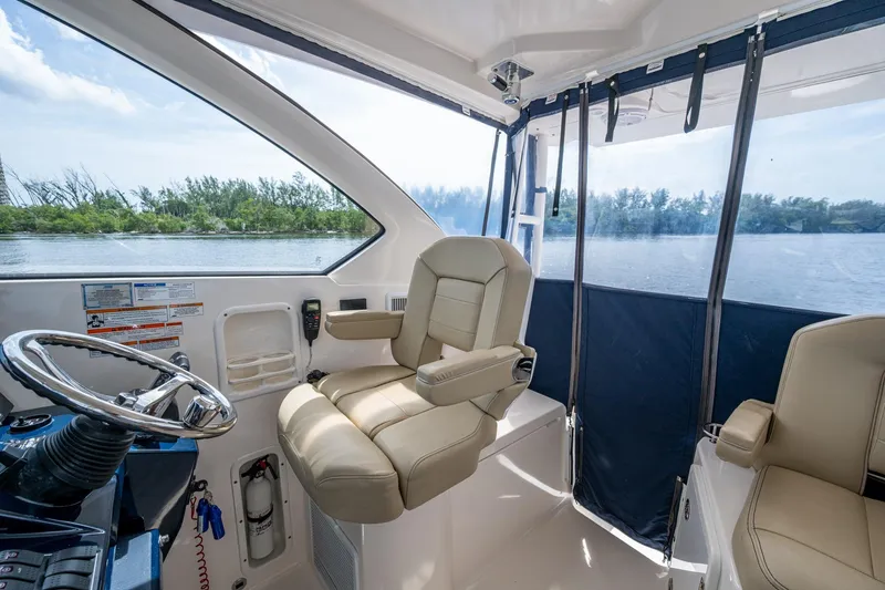 Slide: The Image of Interior of a Pursuit boat with beige seating and steering wheel, overlooking calm waters. - 13