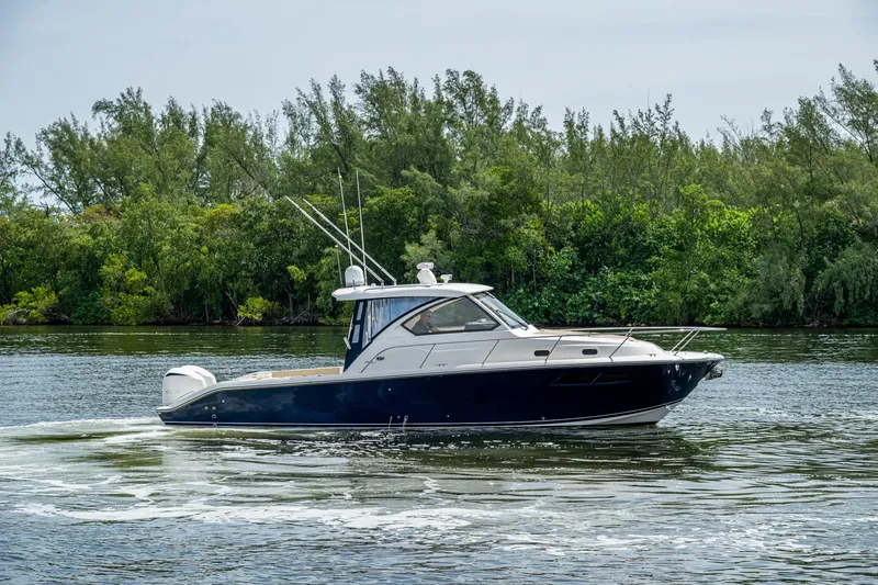 Slide: The Image of Pursuit boat cruising on a calm river with lush green trees in the background. - 14