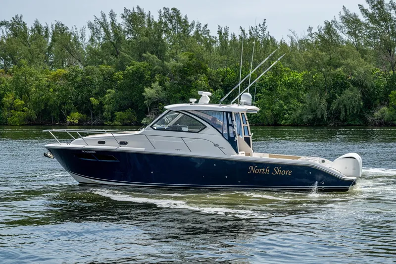 Slide: The Image of Pursuit boat "North Shore" cruising on a calm river with lush greenery in the background. - 15