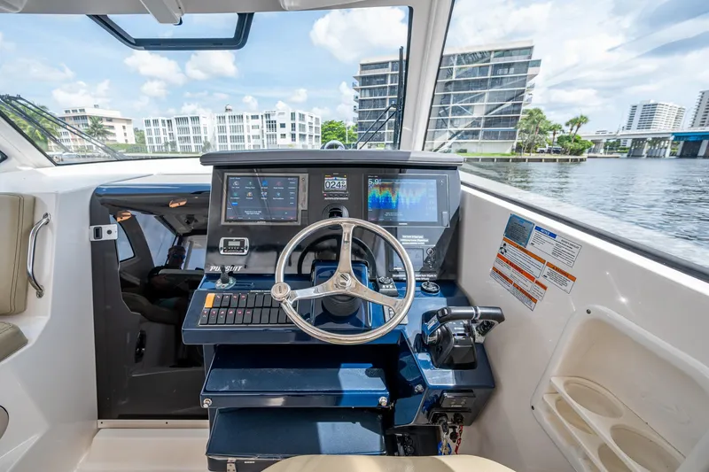 Slide: The Image of Boat cockpit with steering wheel, digital displays, and waterfront view; Pursuit make. - 16