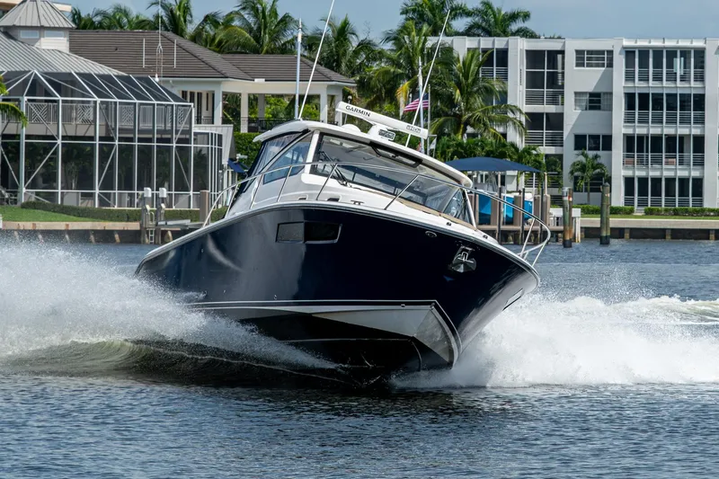 Slide: The Image of Pursuit boat cruising on water near waterfront homes and palm trees. - 17