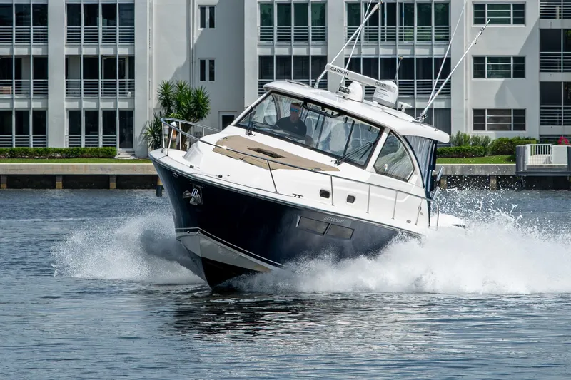 Slide: The Image of Pursuit boat cruising on water near modern waterfront buildings. - 19