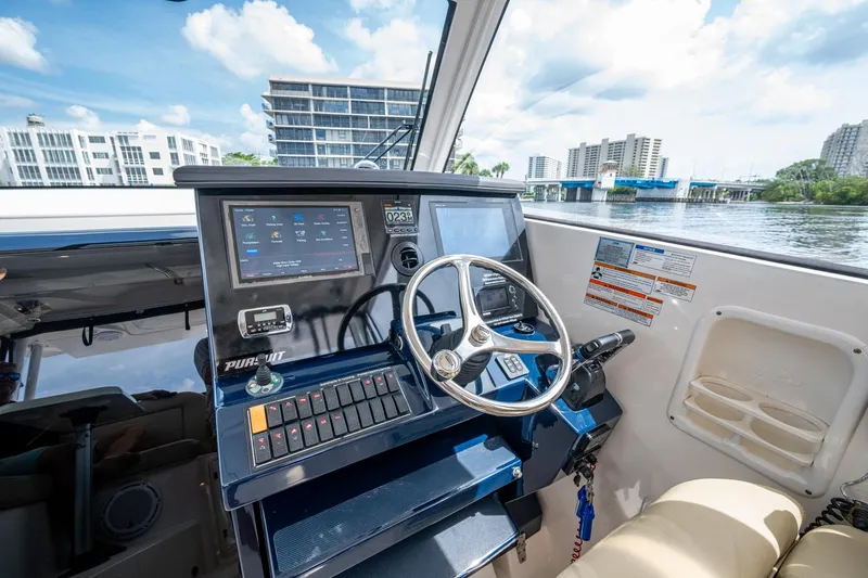 Slide: The Image of Helm of a Pursuit boat with modern controls and waterfront view. - 22