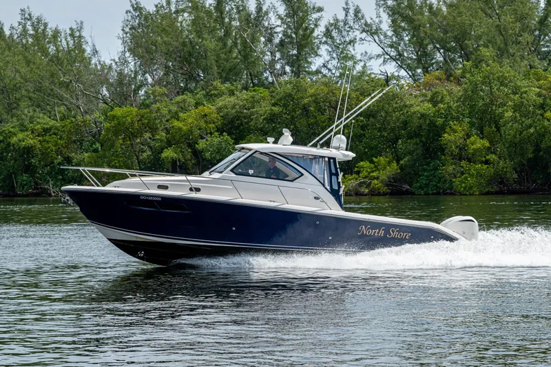 Slide: The Image of A Pursuit boat named "North Shore" cruising on a calm river with lush greenery. - 23
