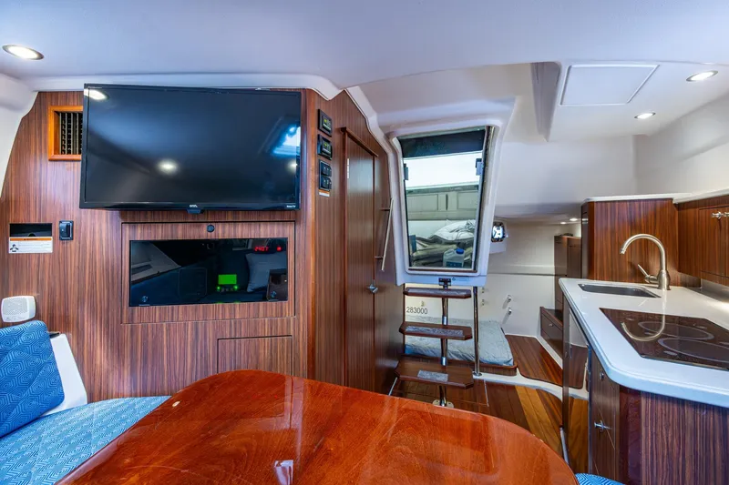 Slide: The Image of Luxurious Pursuit boat interior with wood paneling, TV, kitchenette, and seating area. - 29