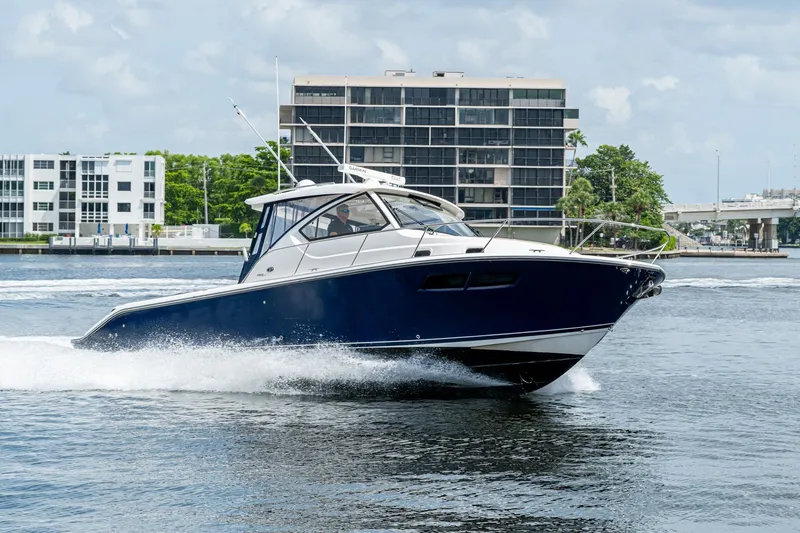 Slide: The Image of Pursuit boat cruising on water near modern buildings and bridge. - 3