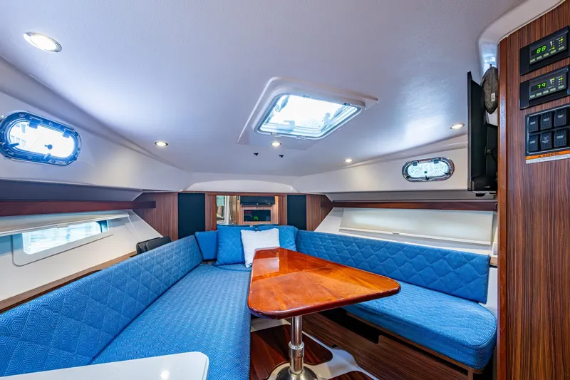 Slide: The Image of Luxurious Pursuit boat interior with blue seating, wooden table, and modern lighting. - 30