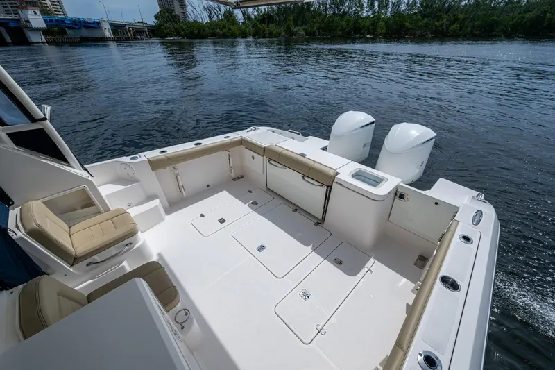 Slide: The Image of Spacious Pursuit boat deck with seating, storage, and dual outboard motors on a calm river. - 32