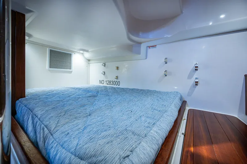 Slide: The Image of Cozy cabin interior with blue bedding in a Pursuit boat, featuring wood accents and white walls. - 33
