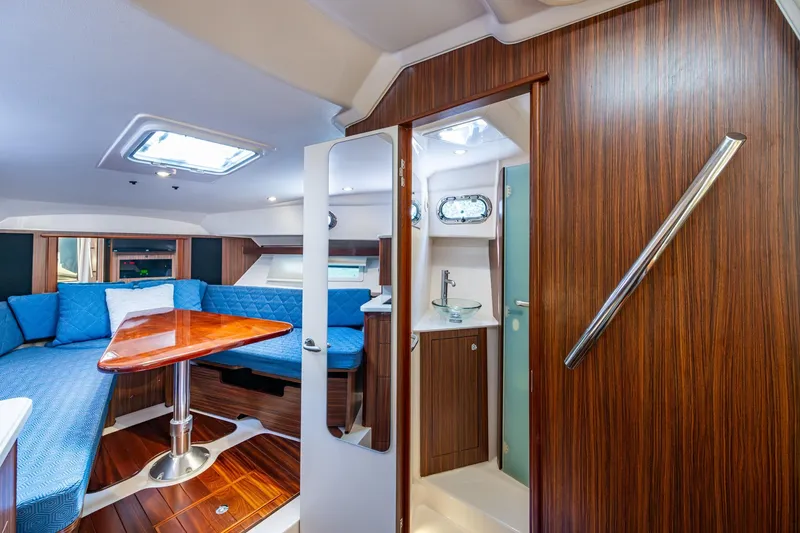 Slide: The Image of Luxurious Pursuit boat interior with wood finish, blue seating, and compact bathroom. - 35