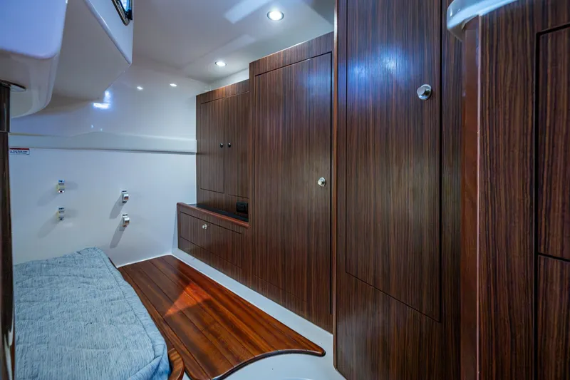 Slide: The Image of Luxurious Pursuit boat cabin interior with wood paneling and cozy bedding. - 36